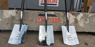 tre blanke spader står op ad et vejskilt i ørestad før første spadestik til den ny kirke