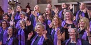 A gospel choir wearing purple scarf swing and sway to the music in a church