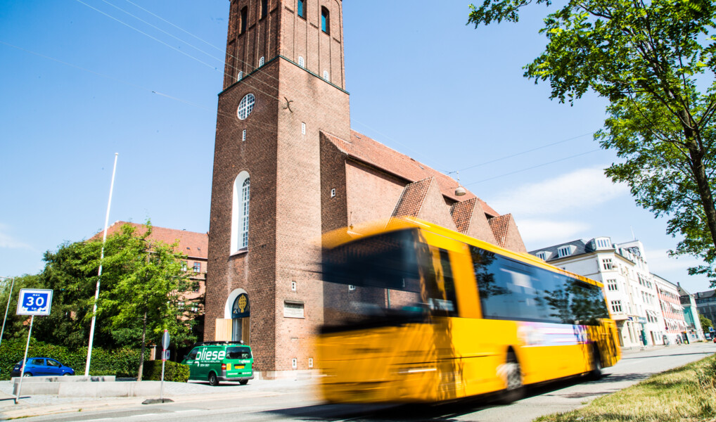 Taksigelseskirken set fra jagtvej med en gul bybus i fart