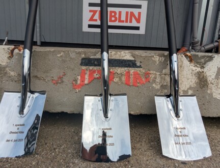 tre blanke spader står op ad et vejskilt i ørestad før første spadestik til den ny kirke