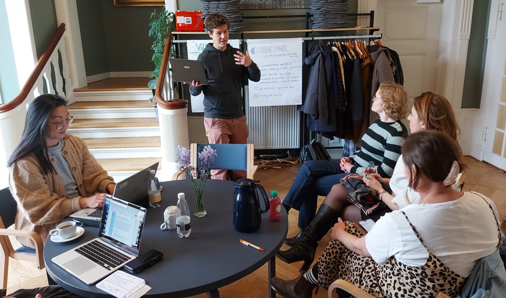 Fem frivillige sidder omkring et bord med kaffe og papirer