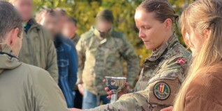 En feltpræst i hærens uniform holder gudstjeneste udenfor blandt soldater