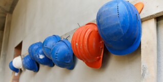 Beskyttelseshjelme - blå, orange og hvide - hænger på væggen på en byggeplads