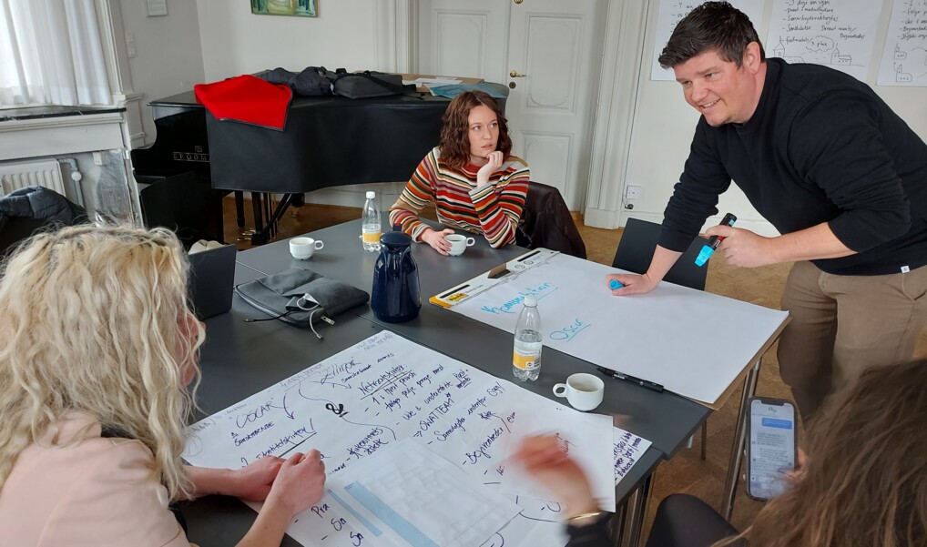 Tre frivillige finder på gode idéer omkring et bord