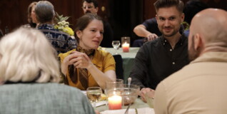 Two people sitting looking at eachother at a set table in a church