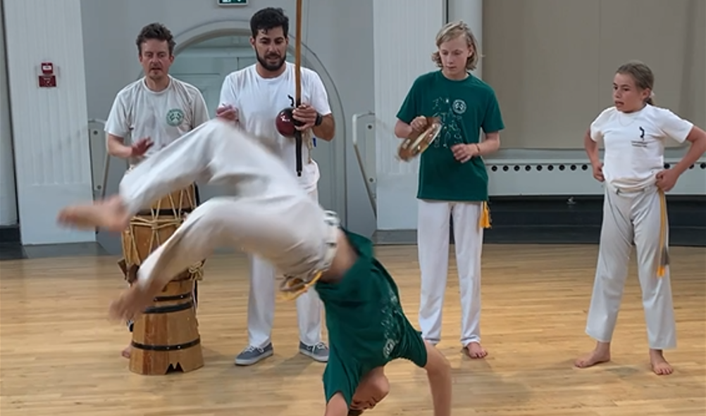 Fem unge mennesker danser capoeira