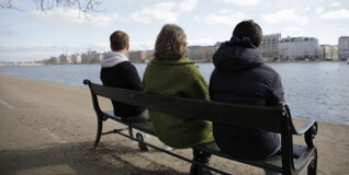 three people sitting on a bench in silence as an illustration of grief and loneliness