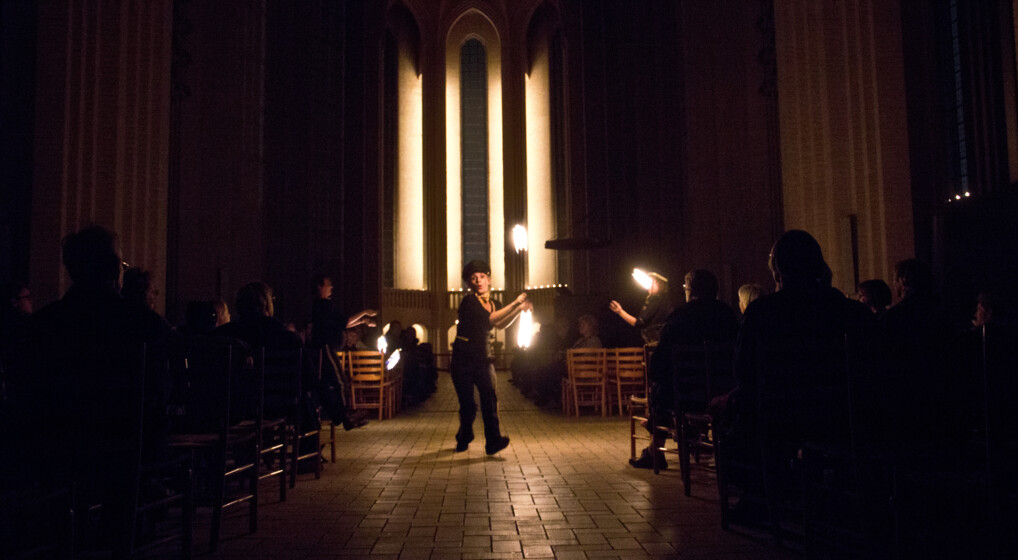 En person jonglerer med ild i en mørklagt kirke