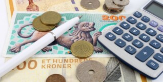 Gamle danske pengesedler ligger spredt ud sammen med en kuglepen og en lommeregner.