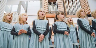 Piger der synger kor foran et orgel