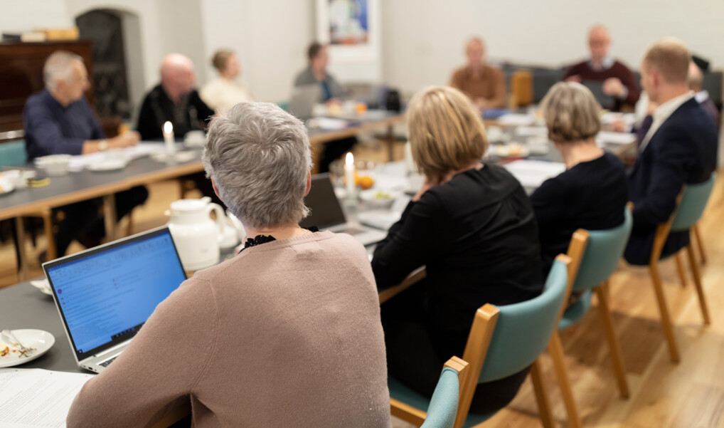 Stiftsrådet sidder i møde omkring et bord med laptops og kaffekander