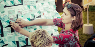 en ung kvinde sætter en postit på en væg ved ungdommens folkemøde