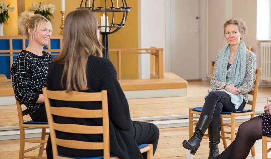 fire kvinder sidder i en rundkreds i en kirke og samtaler