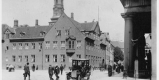 Et sort-hvid billede fra 1910 med automobiler på gaden foran bispegården og domkirken